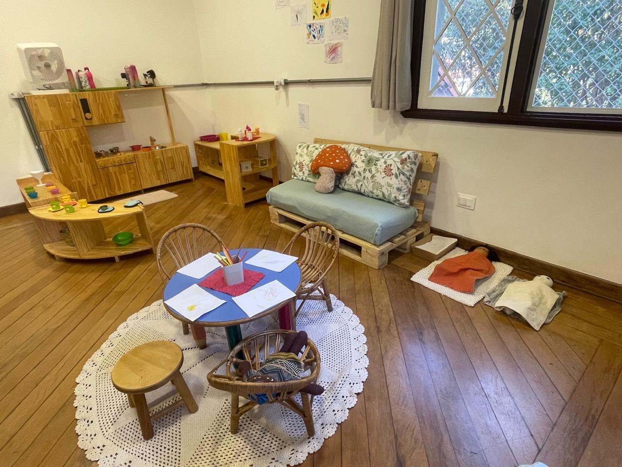 Sala com mesa redonda de desenho, sofá de pallet e cantinho do faz de conta