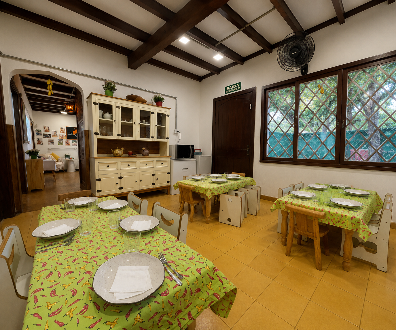 Refeitório da escola com mesas de madeira infantis postas para a refeição