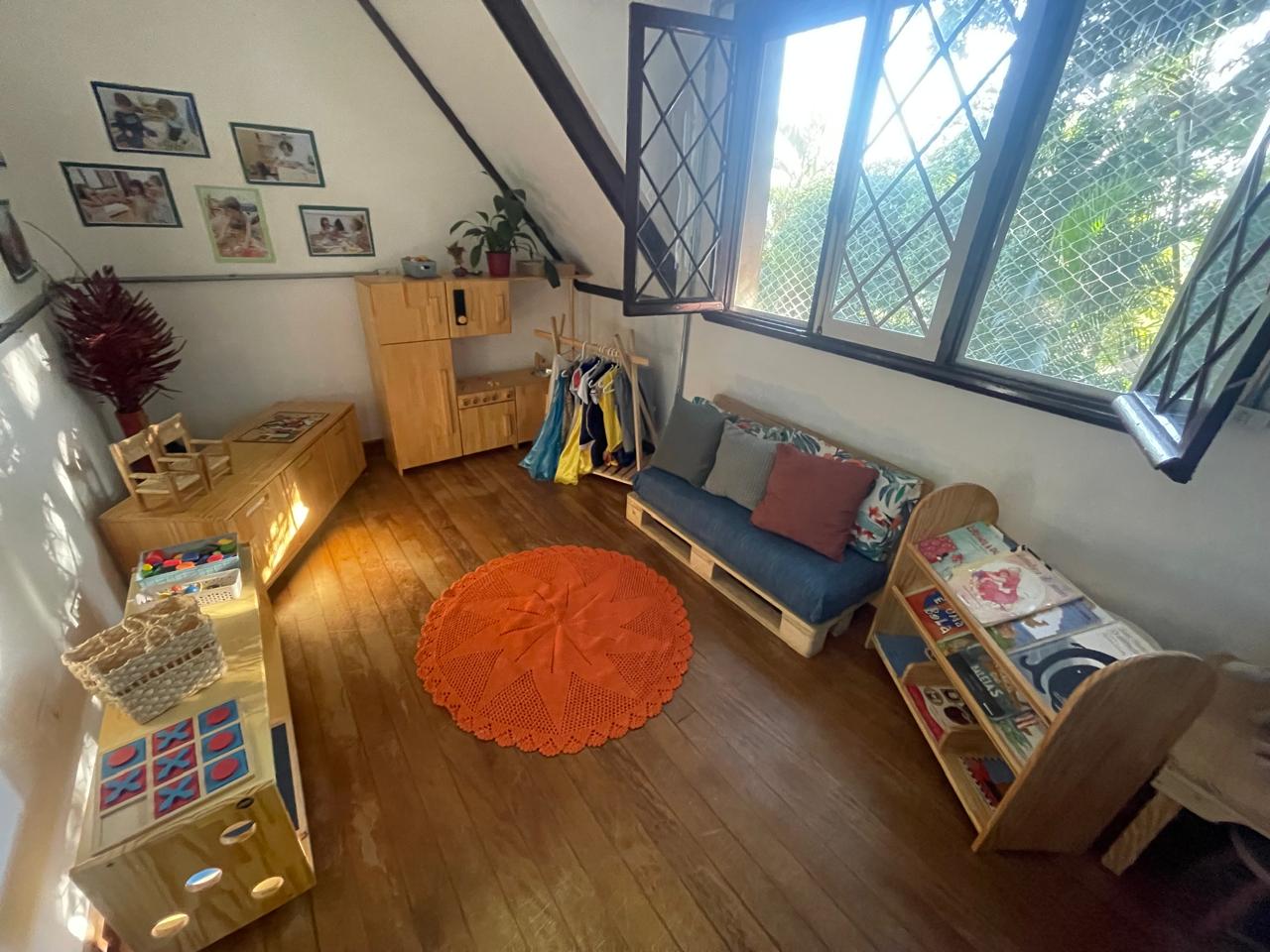 Sala com tapete redondo, cantinho de leitura e arara de fantasias